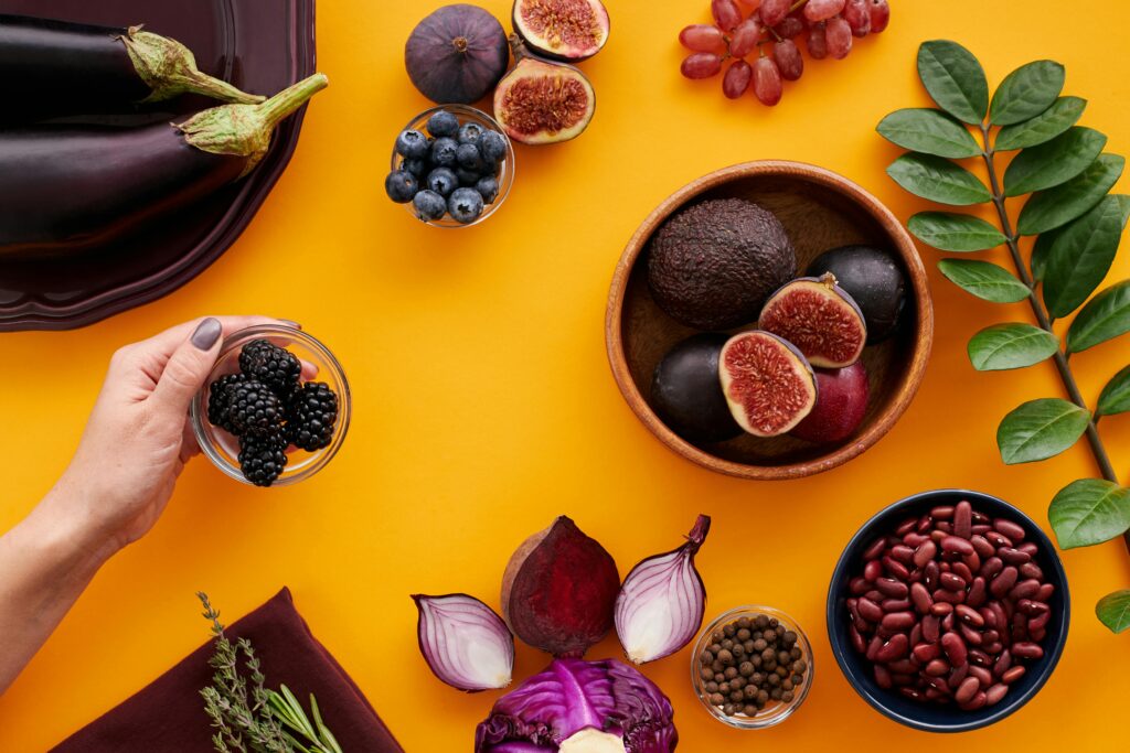 Colorful assortment of fruits and vegetables on a yellow backdrop, highlighting healthy eating.